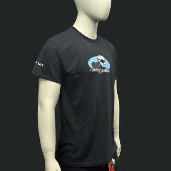 A mannequin displays the men's TROOPER LU T-SHIRT in black, featuring a "Troopy’s Garage" logo with a stylized chest graphic and text detail on the left sleeve.