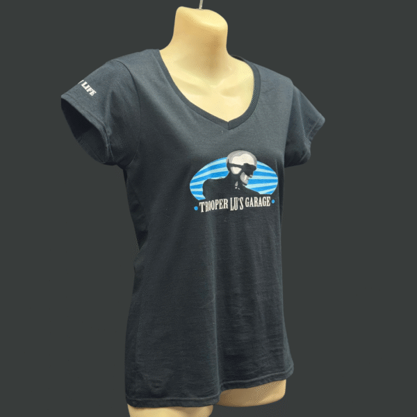 The TROOPER LU T-SHIRT - WOMEN'S is a black tee on a mannequin, featuring a helmeted figure graphic, "TROOPER LU'S GARAGE" text, and "RACER" printed on the left sleeve.