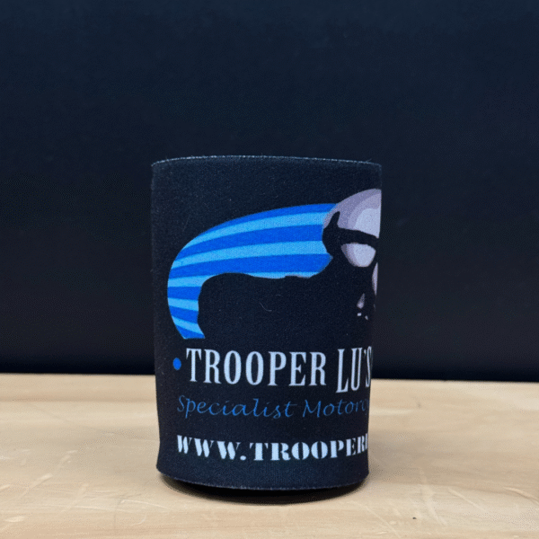 The TROOPER LU'S GARAGE STUBBY COOLER is a black can cooler with a partial skull-in-sunglasses logo, blue stripes, "TROOPER LU’S Specialist Motorcycles" text, and the website URL.