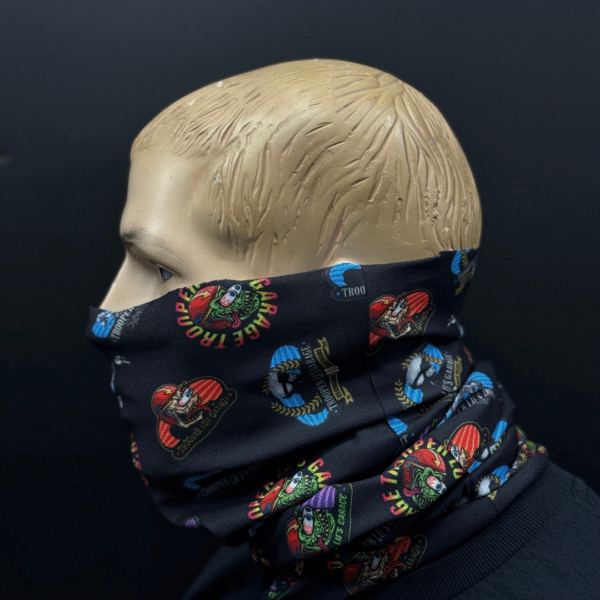 A mannequin head displays the HEADSKINZ TROOPER LU'S NECKWARMER, a black neck gaiter featuring colorful cartoon graphics and text, set against a plain dark background.