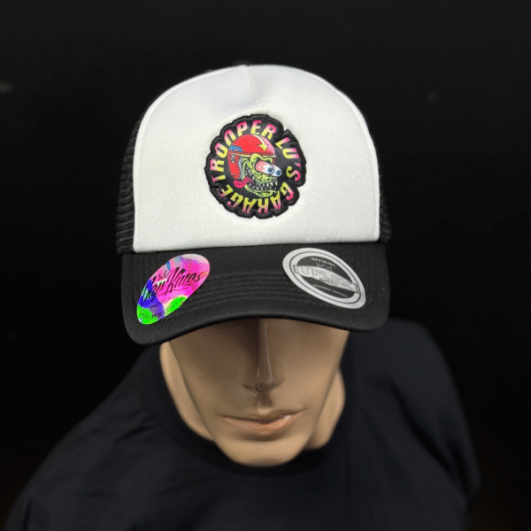 A mannequin displays the TLG's UFLEX SNAP BACK TRUCKER CAP BLACK/WHITE MESH, featuring a colorful "Trooper Luv's Shack" patch and two stickers on the brim, set against a black background.