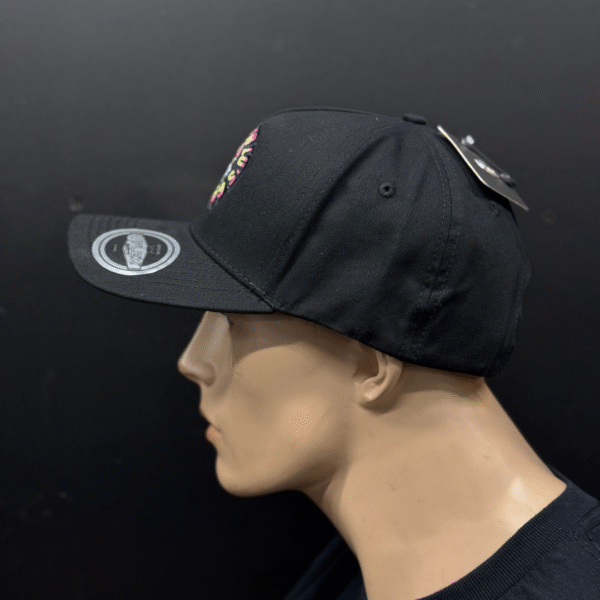 A mannequin head models the TLG's UFLEX PRO STYLE SNAPBACK CAP BLACK, featuring a sticker and tag, set against a plain dark background.