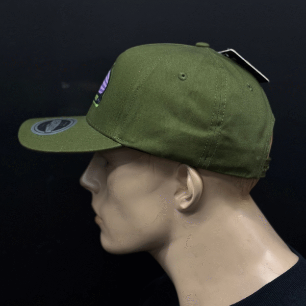 A mannequin head showcases TLG's UFLEX PRO STYLE SNAPBACK CAP GREEN with a flat brim and visor sticker, set against a black background.