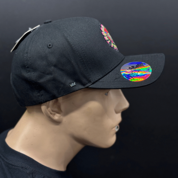 A mannequin displays TLG's UFLEX PRO STYLE SNAPBACK CAP BLACK, featuring a multicolored front logo and a colorful brim sticker, set against a dark background.