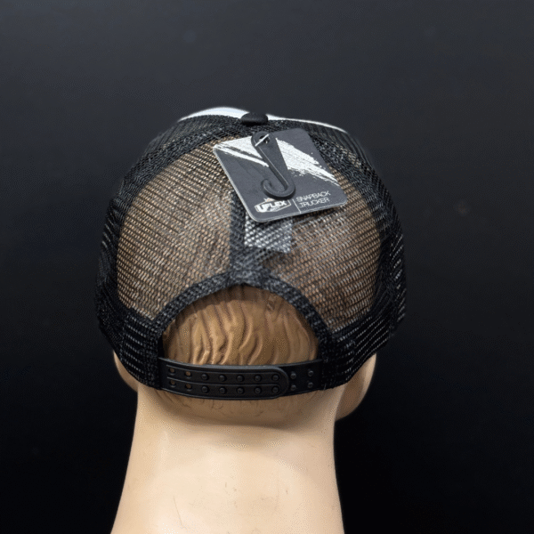 A mannequin head wears TLG's UFLEX Snap Back Trucker Cap in black/white mesh with an adjustable snapback and a tag attached on top.
