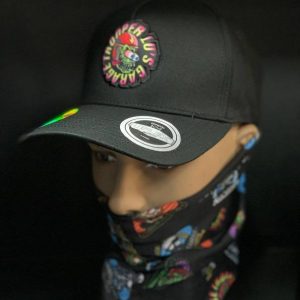 A mannequin sports TLG's UFLEX SNAP BACK TRUCKER CAP with a vibrant logo, along with a matching bandana over its face, against a dark backdrop.