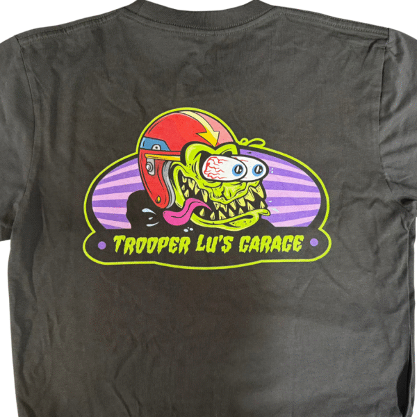 The TROOPER LU MONSTER T-SHIRT - MEN'S is a gray tee featuring a colorful cartoon monster in a red helmet, with "TROOPER LU'S GARAGE" printed beneath the fun design.